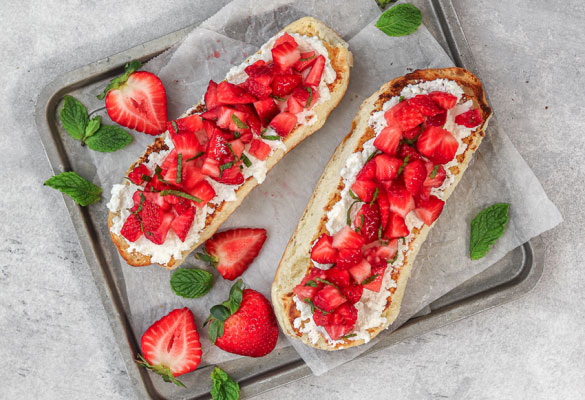 Strawberry bruschetta on two hot dog buns on parchment paper